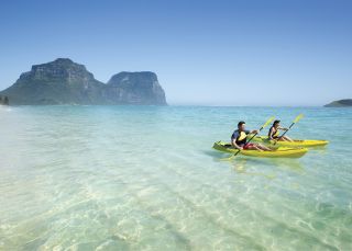 Couple enjoying a scenic kayak by Lagoon Beach on Lord Howe Island with Mount Gower as the backdrop Kayaking, Lord Howe Island