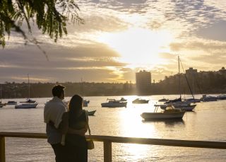 Couple watching the sun setting over North Harbour, Manly