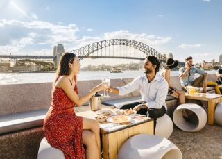 Couple enjoying drinks at sunset by Sydney Harbour