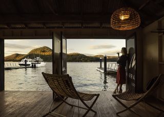 Woman enjoying a beverage with scenic views across Hawkesbury River at Marramarra Lodge, Berowra Waters