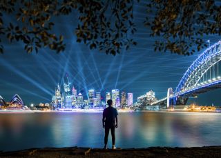 Man watching the City Sparkle light projection and installation on the Sydney Harbour Bridge from Kirribilli, Vivid Sydney 2019