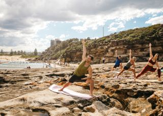 Group enjoying a yoga session by the ocean, Freshwater Beach