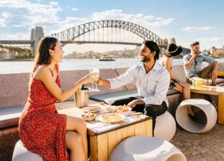 Couple enjoying food and drink with harbour views, Opera Bar, Sydney