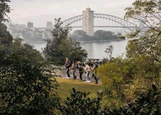 Group enjoying a Dreamtime Southern X tour with Marget Campbell at Balls Head with city skyline, Dreamtime Southern X, Sydney