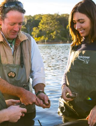 Couple enjoying a tour with Captain Sponge's Magical Oyster Tours on Pambula River, Pambula