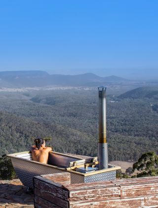 Woman enjoying Bubbletent Australia's outdoor bathtub with scenic views over the Capertee Valley