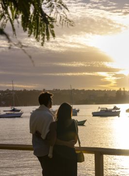 Couple watching the sun setting over North Harbour, Manly