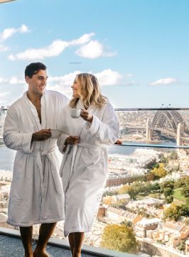 Couple enjoying a coffee and harbour views from their luxurious Crown Towers hotel suite at Crown Sydney, Barangaroo