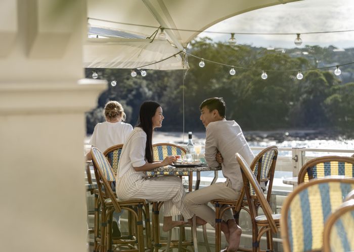 Couple enjoying food and drink with views of Balmoral Beach at Bathers Pavilion, Mosman