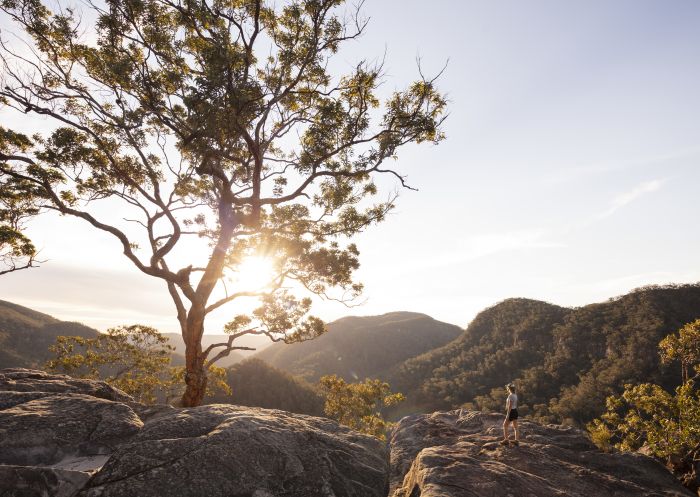Woman watching a scenic sunset over the Hawkesbury Valley from the Vale of Avoca lookout in Grose Vale.