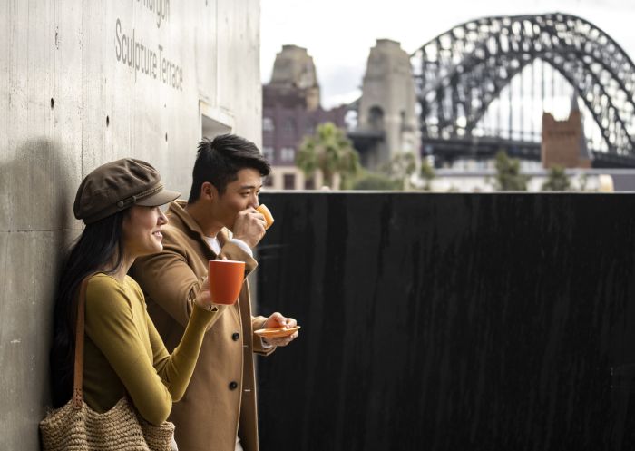 Couple enjoying coffee with views of Sydney Harbour from the MCA Cafe, The Rocks