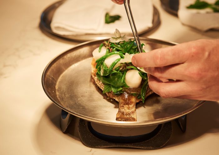 Chef de Cuisine, Rob Cockerill placing the finishing touches on a dish at Bennelong Restaurant, Sydney