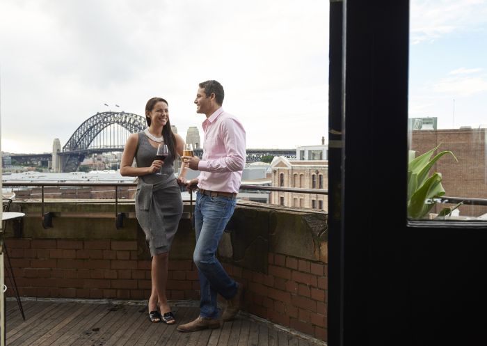 Couple enjoying drinks with Harbour views at Henry Deane cocktail lounge in Hotel Palisade, Millers Point