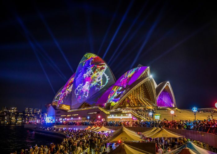Crowds lining the Sydney Harbour shores with the Austral Flora Ballet projection lighting up the Sydney Opera House during Vivid Sydney 2019
