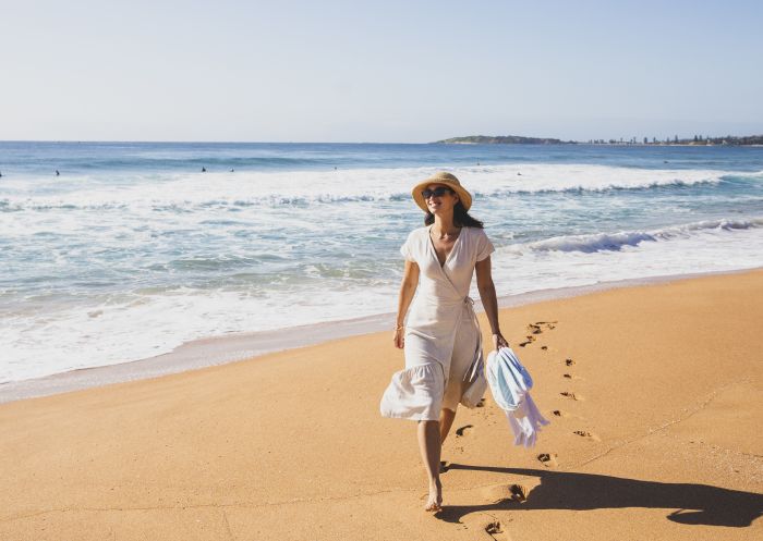 Woman enjoying a morning walk on the beach at North Narrabeen Beach, North Narrabeen