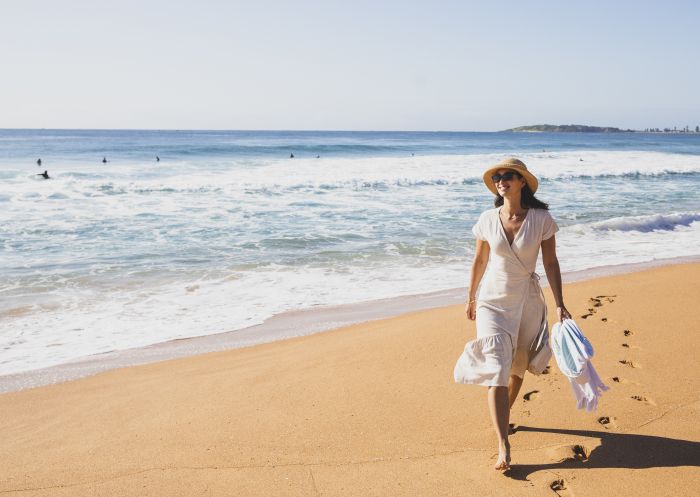 Woman enjoying a morning walk on the beach at North Narrabeen Beach, North Narrabeen