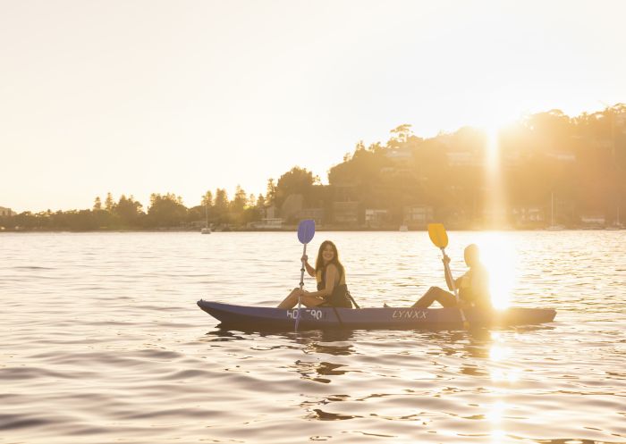 Couple enjoying a sunrise kayaking experience in Pittwater with Pittwater Kayak Tours, Palm Beach.
