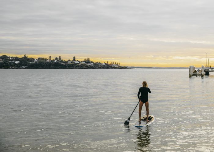 Man enjoying a morning of stand up paddleboarding in Port Hacking near Bundeena Wharf, Bundeena