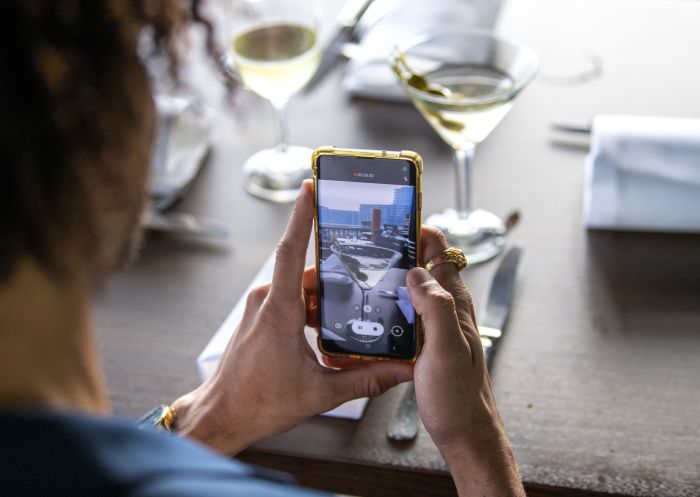 Man taking a photo of a cocktail at Cafe Sydney