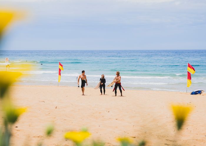 Surfers heading into the waves at North Narrabeen Beach, North Narrabeen