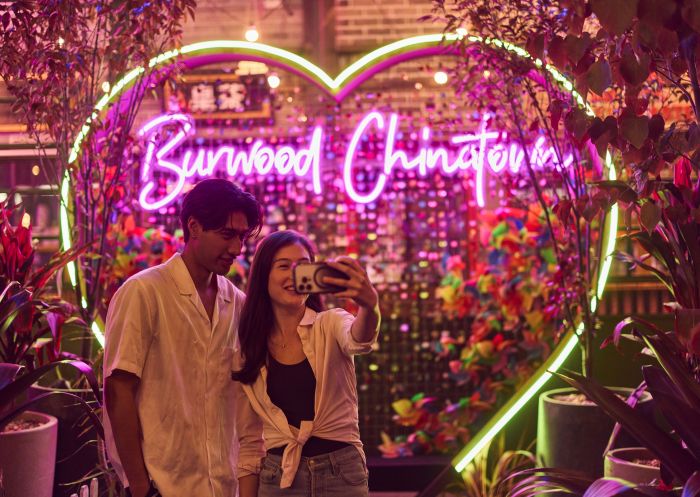Two people taking photos in front of a neon sign, Burwood Chinatown, Burwood