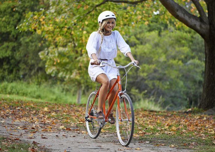 Woman riding a bike in autumn through Centennial Parklands, Sydney east
