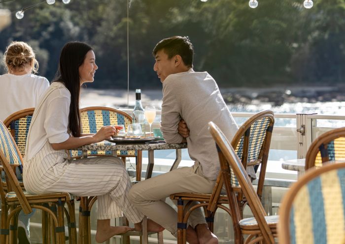 Couple enjoying food and drink with views of Balmoral Beach at Bathers Pavilion, Mosman