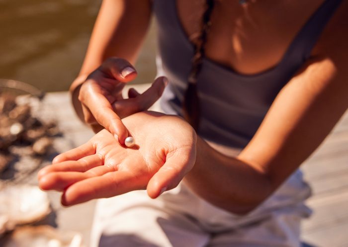 Woman holding pearl at Broken Bay Pearl Farm, Mooney Mooney