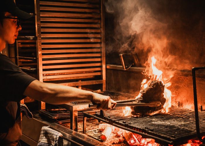 Chef cooking steak on the grill at Bistecca, Sydney CBD