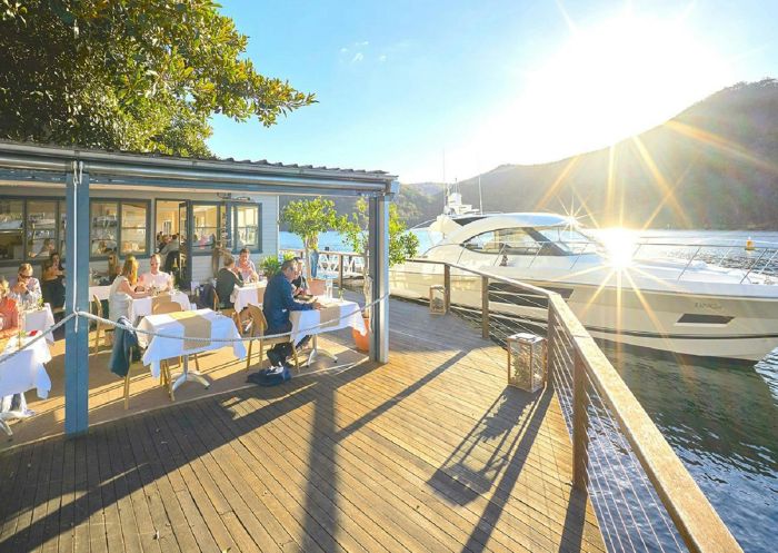 People dining on the sunny deck at Cottage Point Inn, Cottage Point