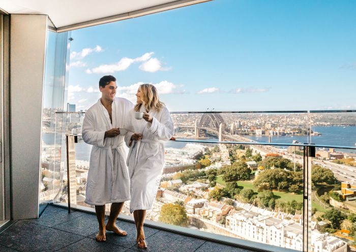 一对夫妇在悉尼市区巴兰加鲁皇冠悉尼酒店的豪华皇冠塔酒店套房里享用咖啡，欣赏海港美景