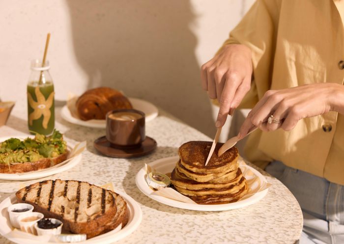 Sandy's, Sydney Olympic Park Woman's hand and fingers shown cutting pancakes with a knife at Sandy's in Sydney Olympic Park