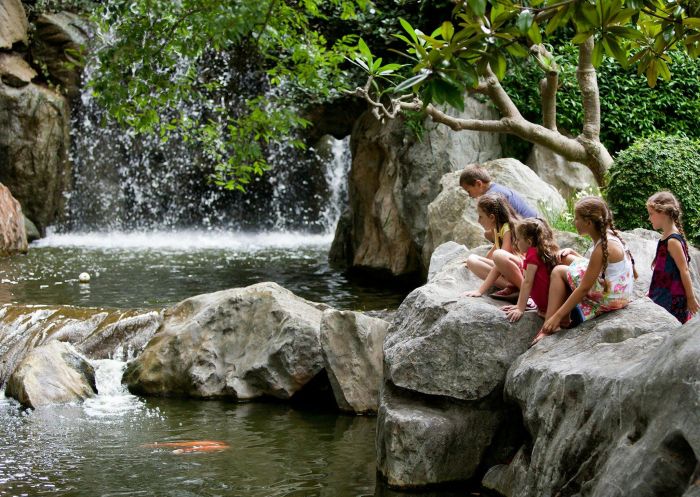 Chinese Garden of Friendship, Darling Harbour Kids sitting on a rock at a lake in the Chinese Garden of Friendship at Darling Harbour