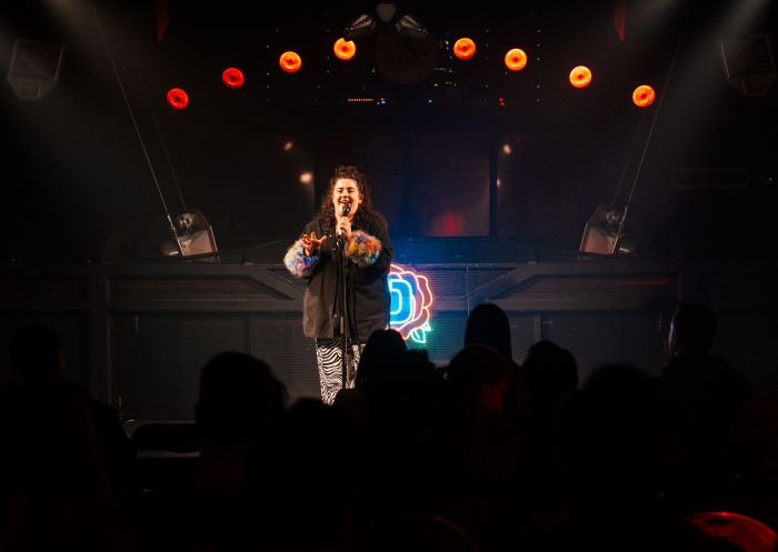 Ness Studios performer on stage with fluffy jacket, iD Comedy Club, Darlinghurst - Credit: iD Comedy Club