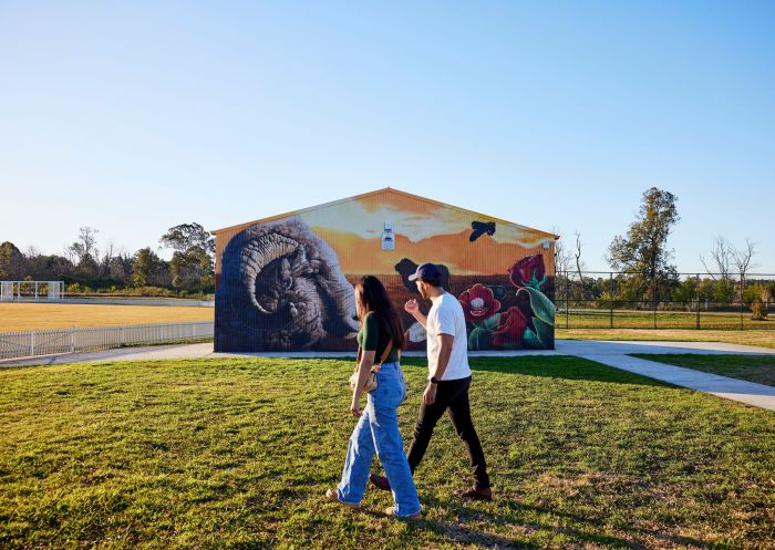Couple walking past Artist - Sekt Compton (Blackbook Ink) Artwork - Golden Graze, Camden Town Farm, Camden