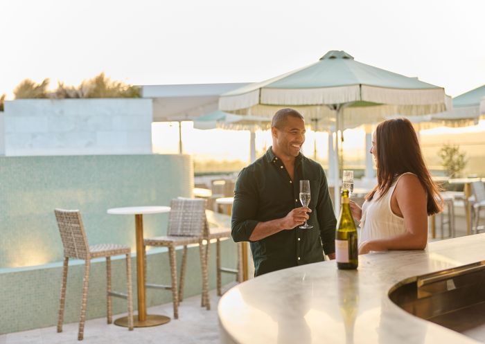 Couple drinking champagne at bar at sunset, Theo's Rooftop Bar, Penrith