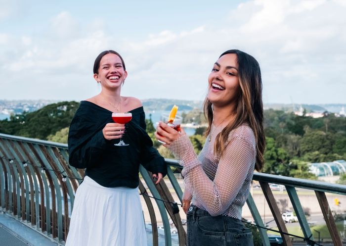Friends laughing with drinks on the balcony, The Library Bar, Sydney
