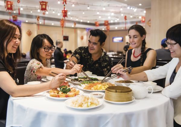 Friends enjoying a prosperity toss at Golden Century Restaurant  during Chinese New Year in Chinatown, Sydney City 