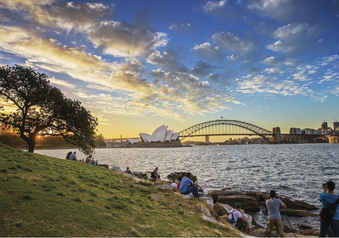 People watching the sun setting over the Sydney Opera House and Sydney Harbour Bridge from Royal Botanic Garden Sydney Harbour in Summer