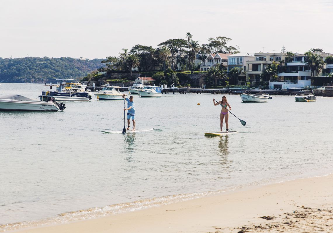 Couple enjoying a morning of stand up paddleboarding at Watsons Bay in Sydney's eastern suburbs