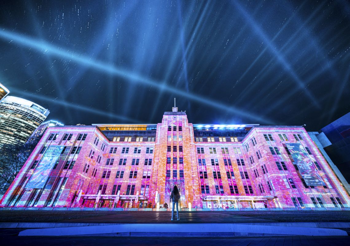 Man enjoying the Let Me Down light projection on the Museum of Contemporary Art (MCA) Australia building in The Rocks during Vivid Sydney 2019