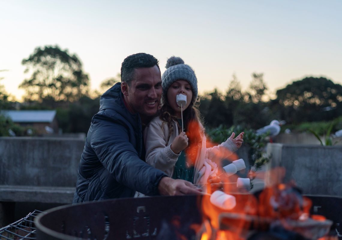 Family relaxing and roasting marshmallows at their Cockatoo Island waterfront campsite
