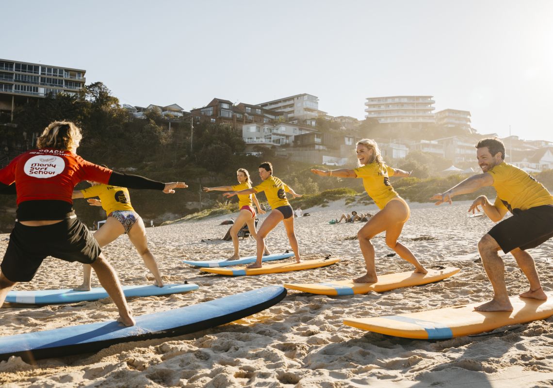 Adults enjoying a learn to surf experience with Manly Surf School at Freshwater Beach
