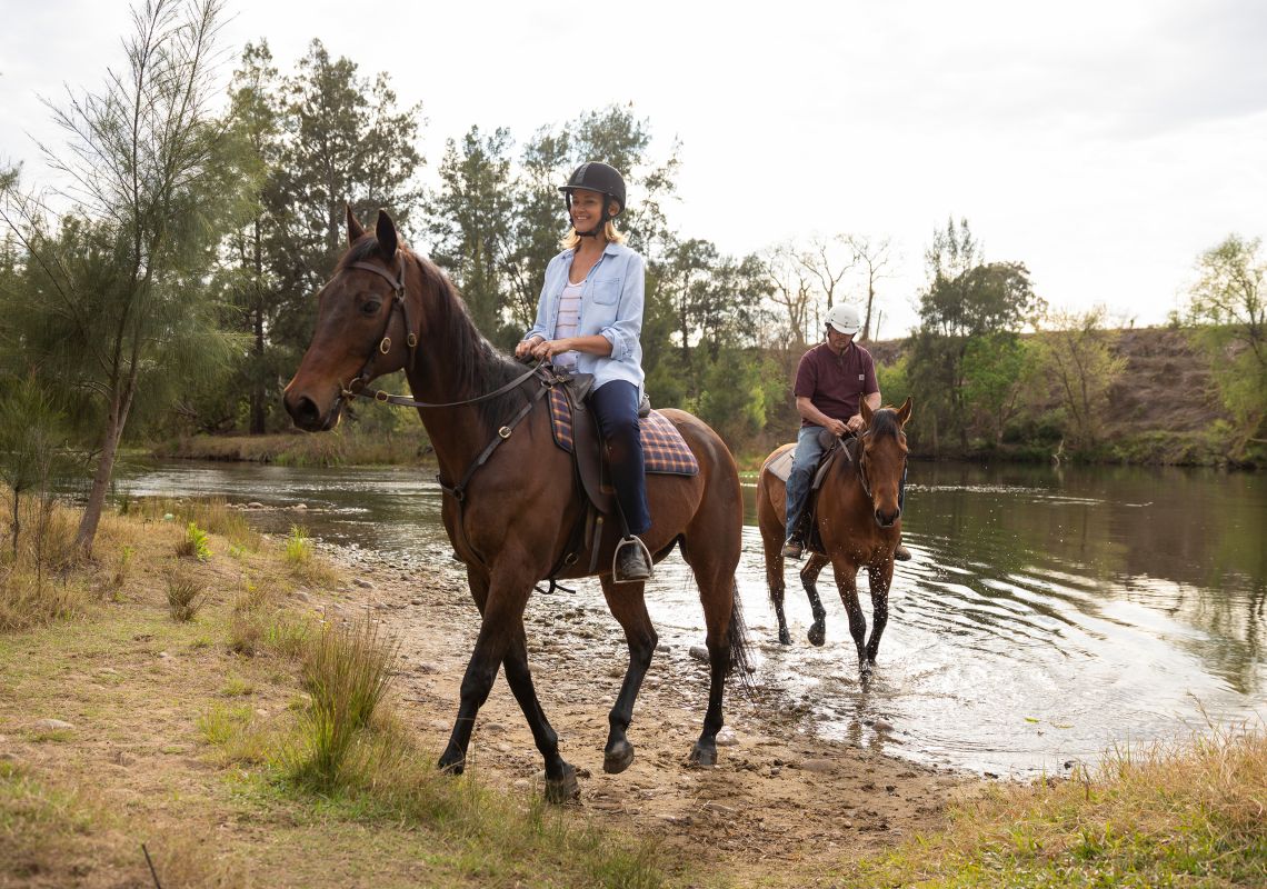 Couple enjoying a horseriding experience along the Hawkesbury River with Hawkesbury Valley Equestrian Centre, Yarramundi