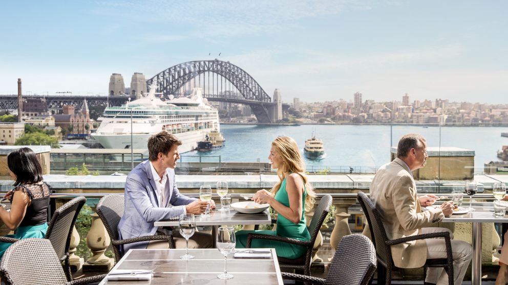 Couple enjoying a lunch with views of a cruise ship at Cafe Sydney on the rooftop of Customs House, Circular Quay