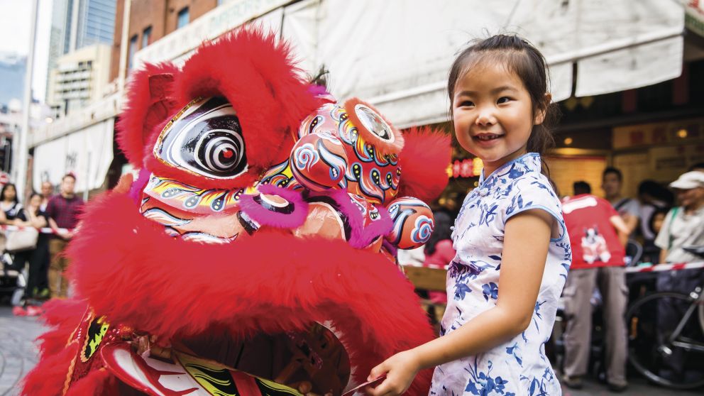 Young girl places a red packet into the mouth of the dragon during Chinese New Year in Chinatown, Sydney City