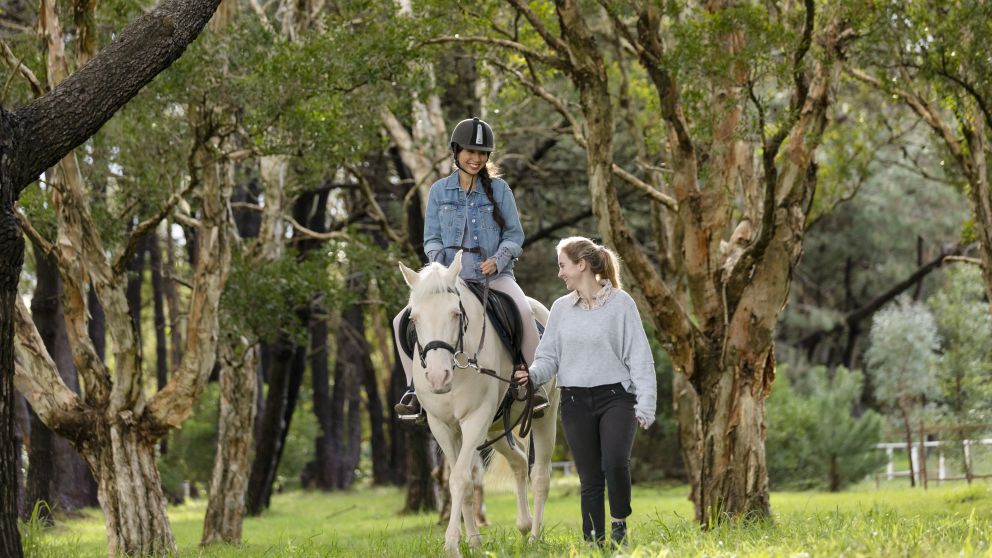 Woman enjoying a horse riding experience with East Side Riding Academy in Centennial Park, Sydney