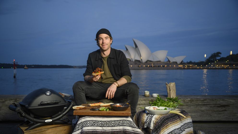 Hayden Quinn cooking Lemongrass Pork Roll with Opera House in background, Sydney Harbour