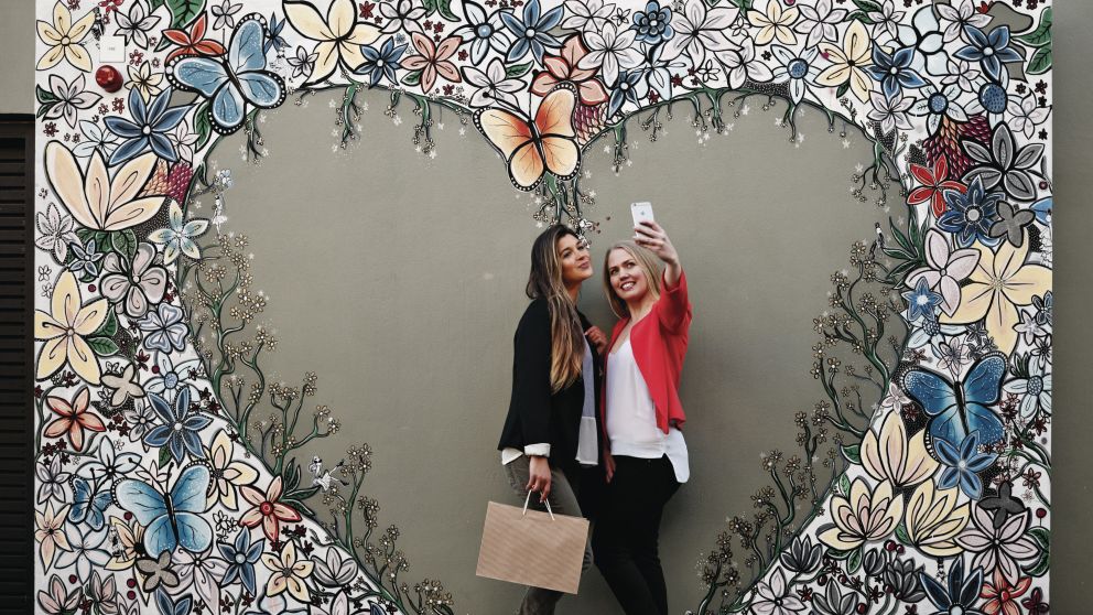 Friends taking a selfie in front of Aaron Favaloro street art, Paddington