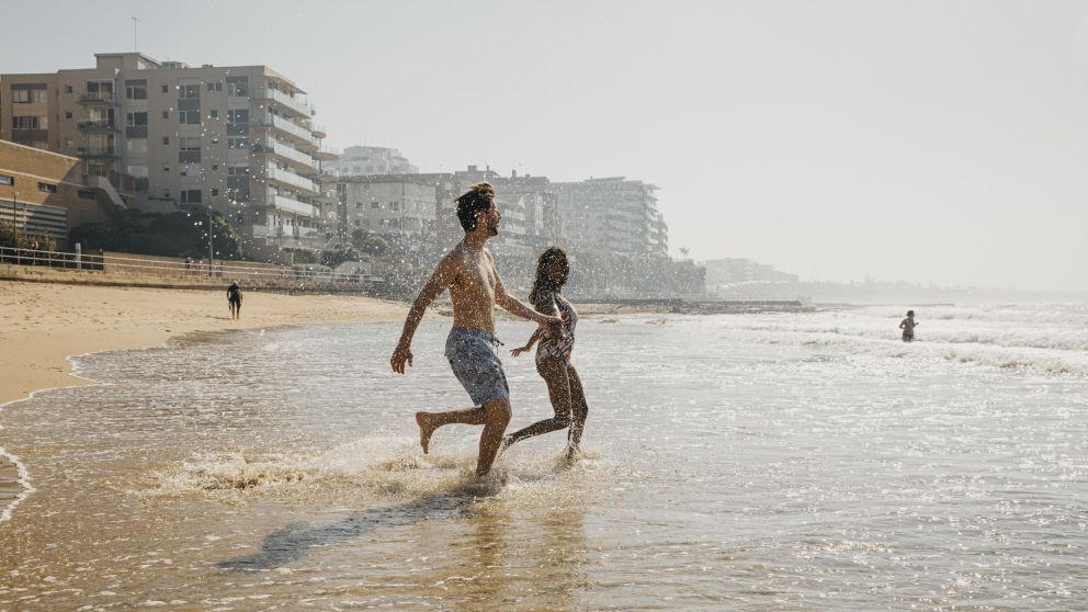 Couple running into the surf at South Cronulla Beach, Cronulla